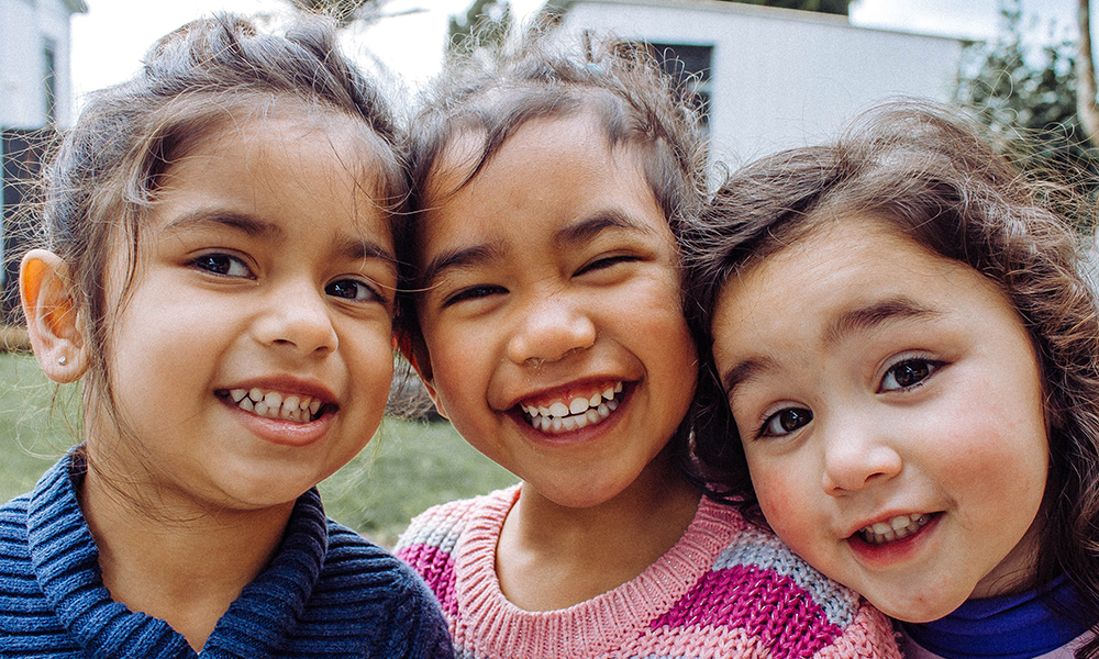 Closeup of three smiling girls with brown eyes and wavy brown hair