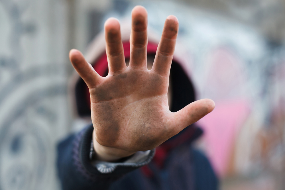 Closeup of the open palm of a dirty hand of a person unfocused in the background